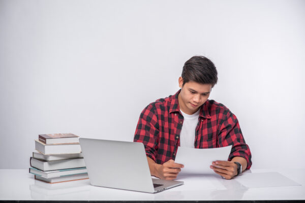 A man using a laptop in the office and doing a document analysis